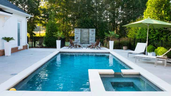 Modern backyard pool with lounge chairs and greenery