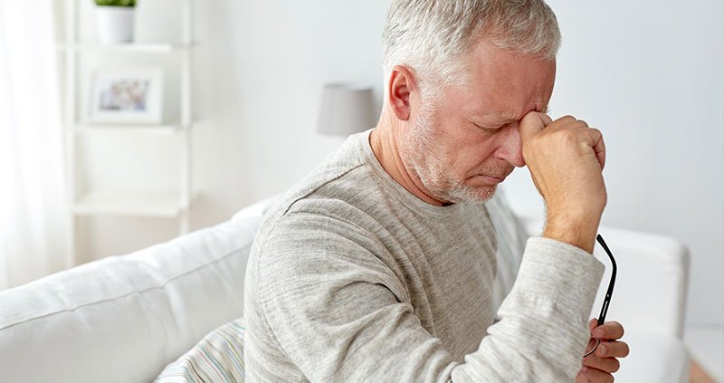 Person sitting indoors holding eyeglasses