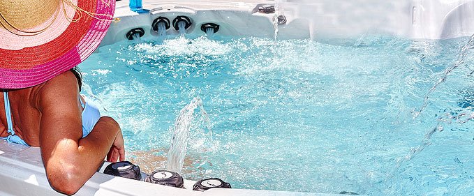 women seating at the edge of an outdoor hot tub with water jets running