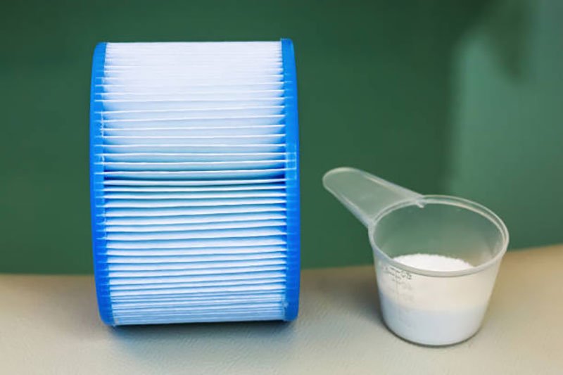 Hot tub filter beside a scoop of cleaning powder.