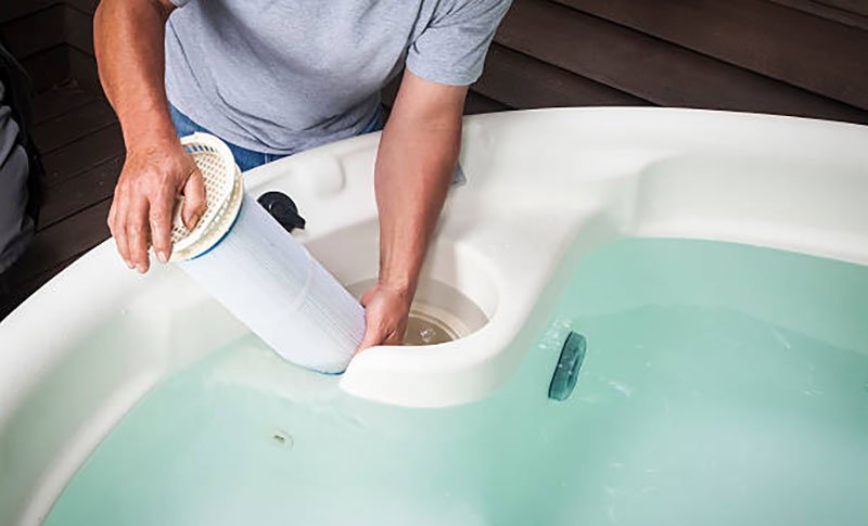 Person removing a hot tub filter for cleaning
