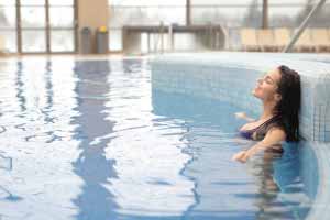 Person relaxing in an indoor pool near tile edge