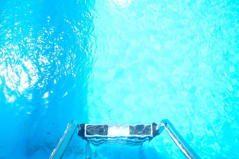 Pool ladder leading into clear blue water