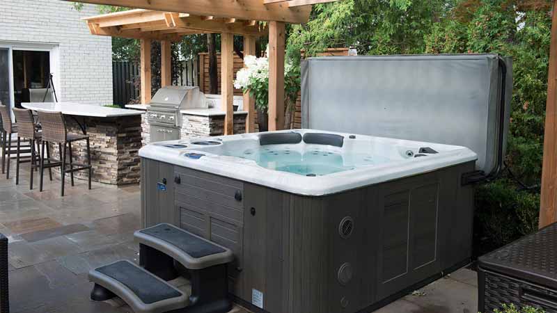 Outdoor hot tub with its cover open on a patio