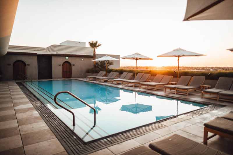 Rooftop swimming pool with lounge chairs and umbrellas at sunset